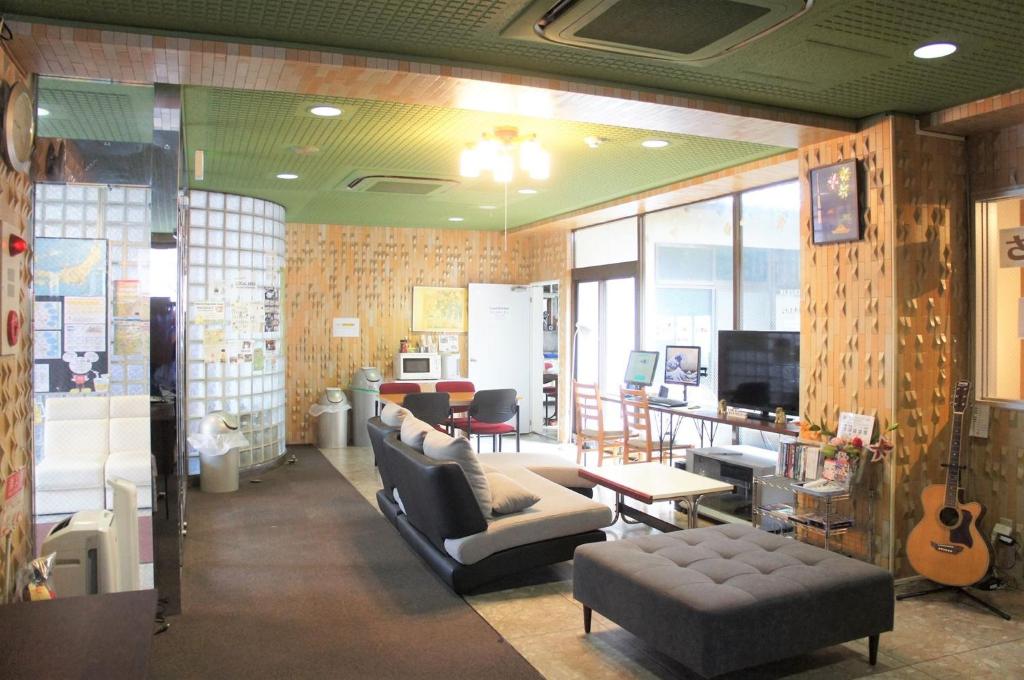 Juyoh Hotel في طوكيو: غرفة معيشة بها أريكة وكراسي وتلفزيون