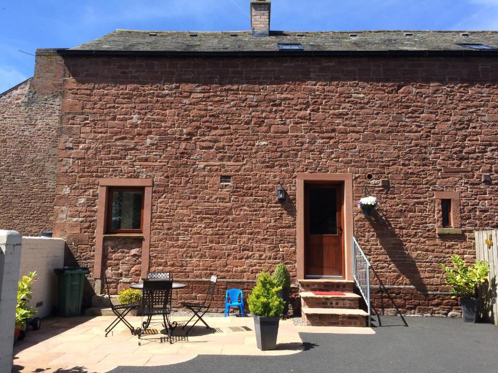 a brick building with a table and chairs in front of it at The Old Bothy in Wigton
