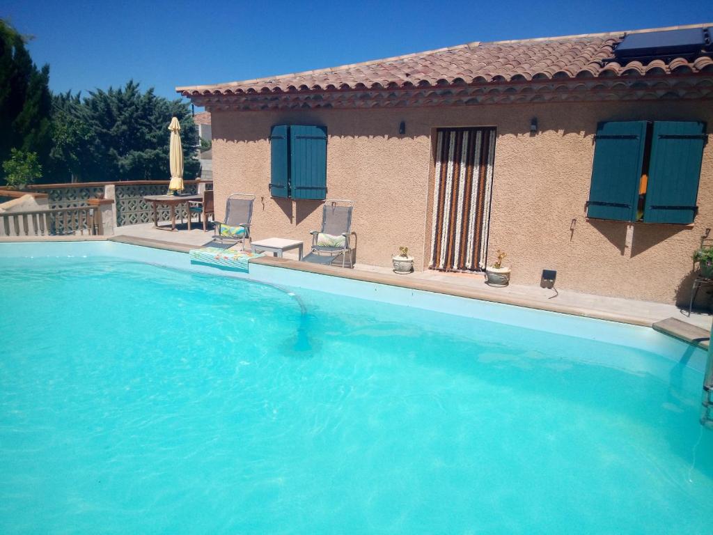 a large swimming pool with a house with blue doors at Olive View in Puissalicon