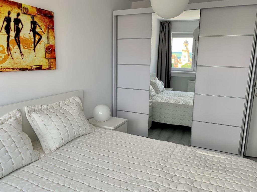 a bedroom with a white bed and a mirror at Citadel Residence in Alba Iulia