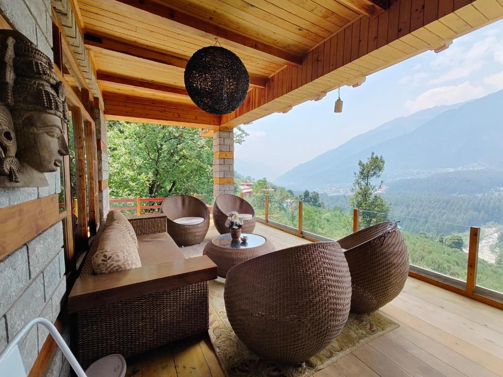 a porch with chairs and a view of a mountain at SaffronStays The Amlyn, Manali - unobstructed views of Beas river and the Himalayas in Manāli