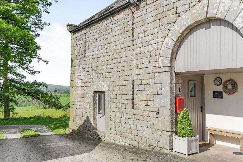 ein Backsteingebäude mit einer Tür und einem Baum davor in der Unterkunft Berts Cottage in Great Ormside