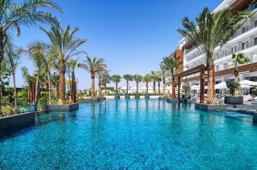 uma piscina com palmeiras em frente a um edifício em Amanti, MadeForTwo Hotels - Ayia Napa em Agia Napa