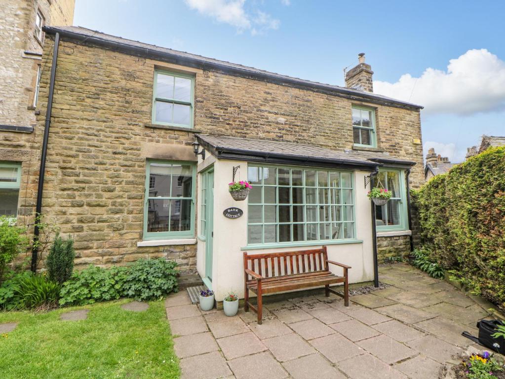 a brick house with a bench in front of it at Bank Cottage in Buxton