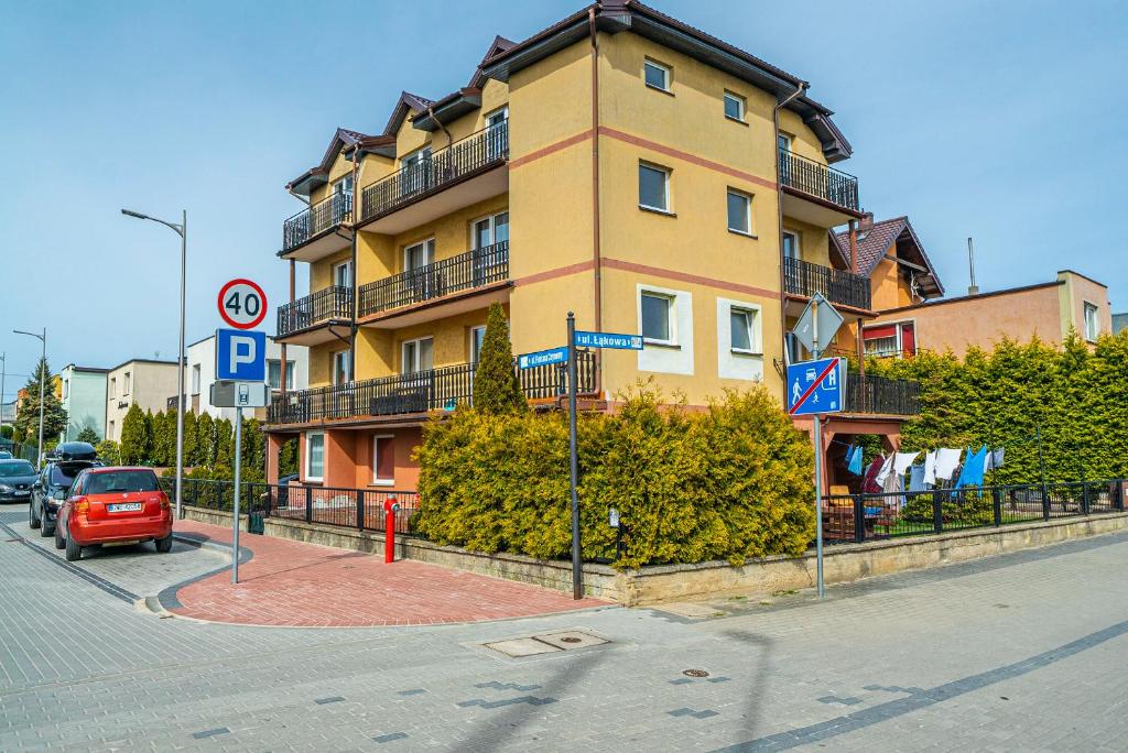 um edifício numa rua com um carro vermelho à frente em Pokoje Alga em Władysławowo