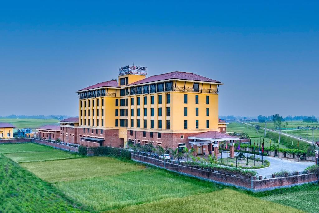 a large yellow building on top of a green field at Soaltee Westend Premier in Nepālganj