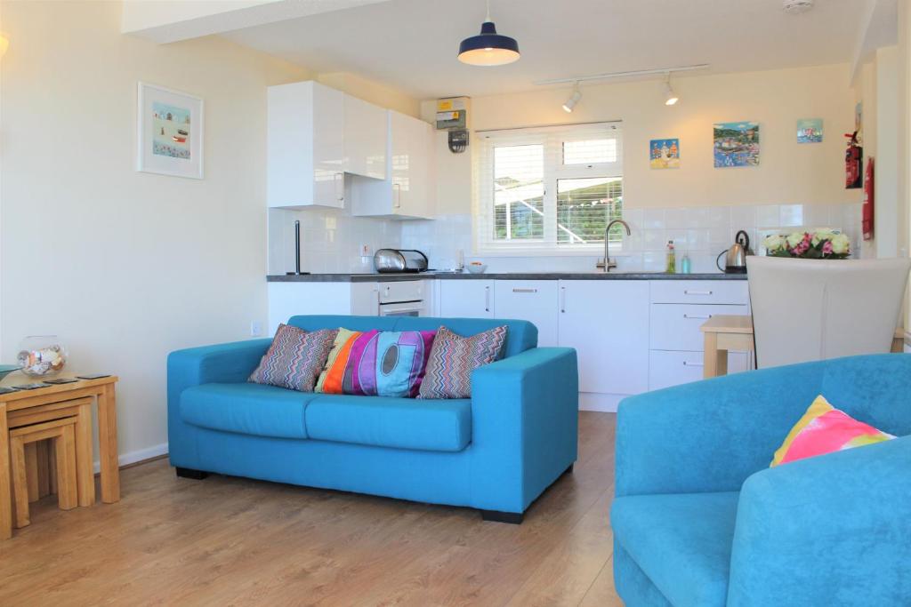 a living room with a blue couch and a kitchen at Sandcastles - Mount Brioni in Downderry