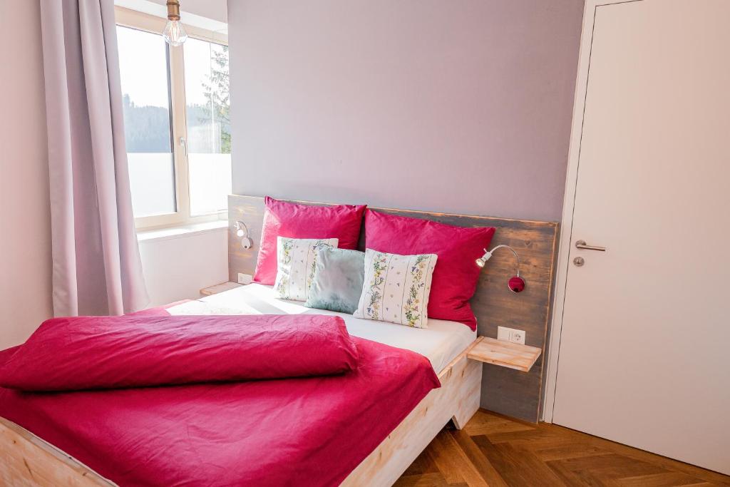 sypialnia z łóżkiem z czerwoną pościelą i oknem w obiekcie Bienenkunde Lunz w mieście Lunz am See