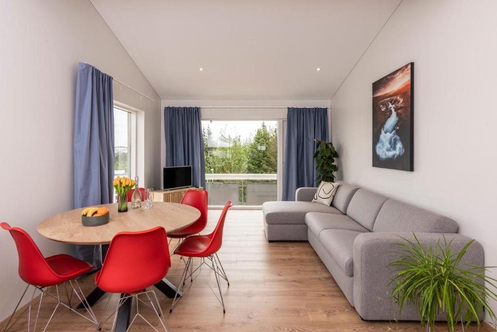 a living room with a couch and a table and red chairs at Lundur Apartments in Reykjavík