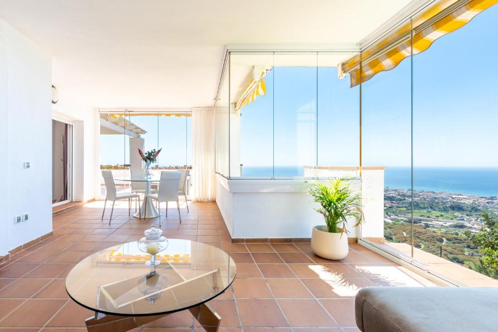 ein Wohnzimmer mit einem Tisch und großen Glasfenstern in der Unterkunft Venus Malaga Apartamento de Lujo in Rincón de la Victoria