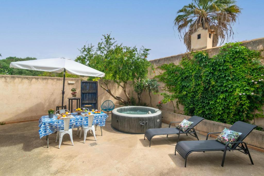a table and chairs with an umbrella and a pool at Can Pontet in Vilafranca de Bonany