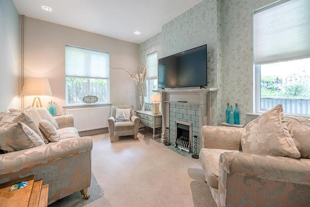 a living room with couches and a television and a fireplace at Saxon Lodge Cottage Felixstowe Air Manage Suffolk in Felixstowe