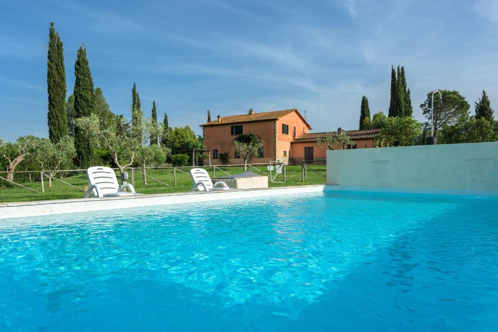 a swimming pool with chairs and a house at Agriturismo Zuccherini in Buriano