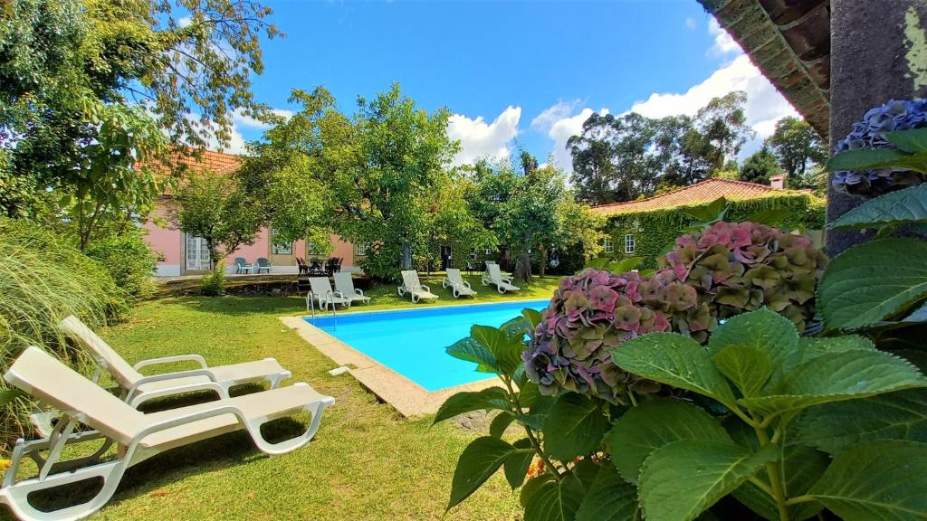 einen Hinterhof mit einem Pool und einem Garten mit Stühlen und Blumen in der Unterkunft Casa da Roseira in Ponte de Lima
