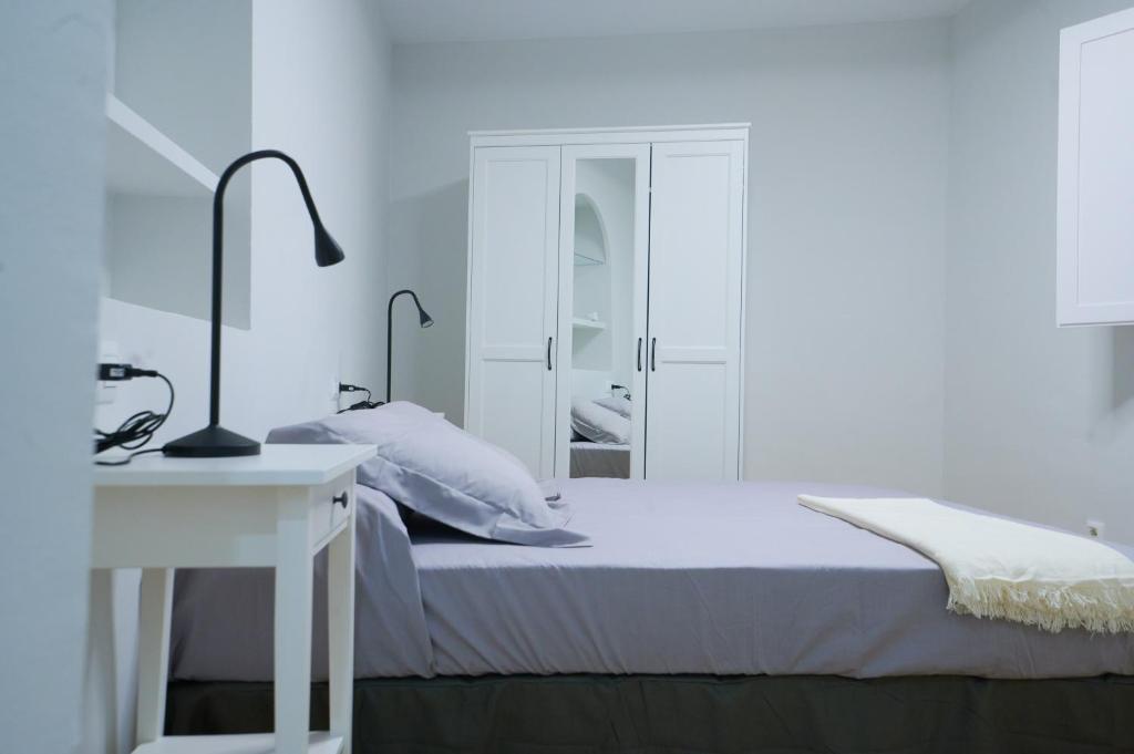 a white bedroom with a bed and a desk at Pretty town hall apartment in Tarragona