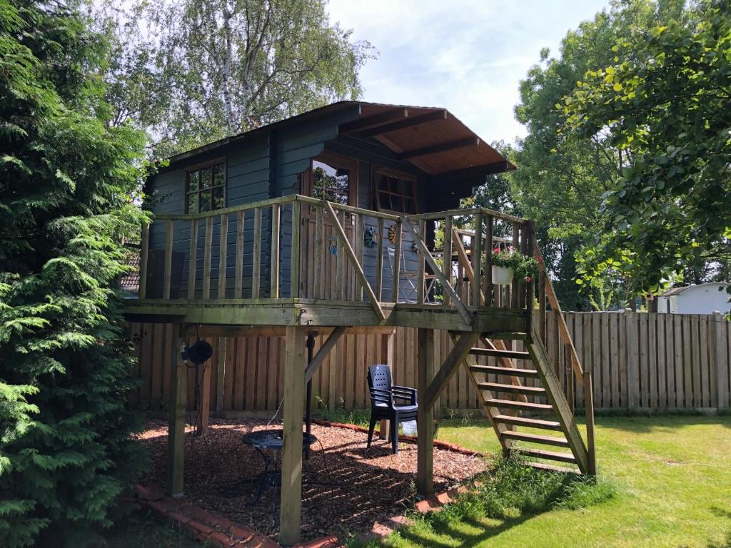 a tree house with a staircase in a yard at Treehouse op het platteland van Huize Ouwervelden in Centrum