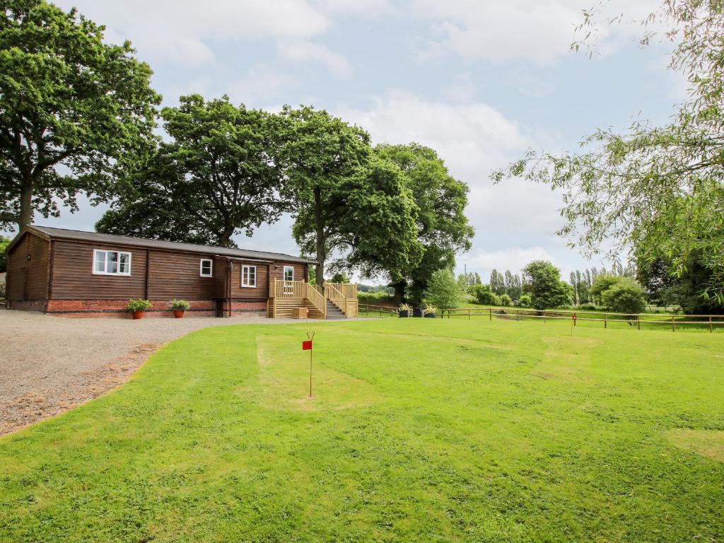 a large yard with a house in the background at The Log Cabin in Tenbury
