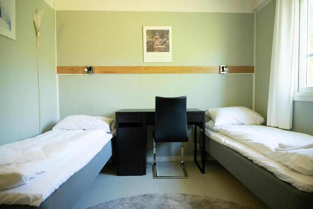 Zimmer mit 2 Betten und einem Schreibtisch mit Stuhl in der Unterkunft Sandvik Gjestegård in Sandvik