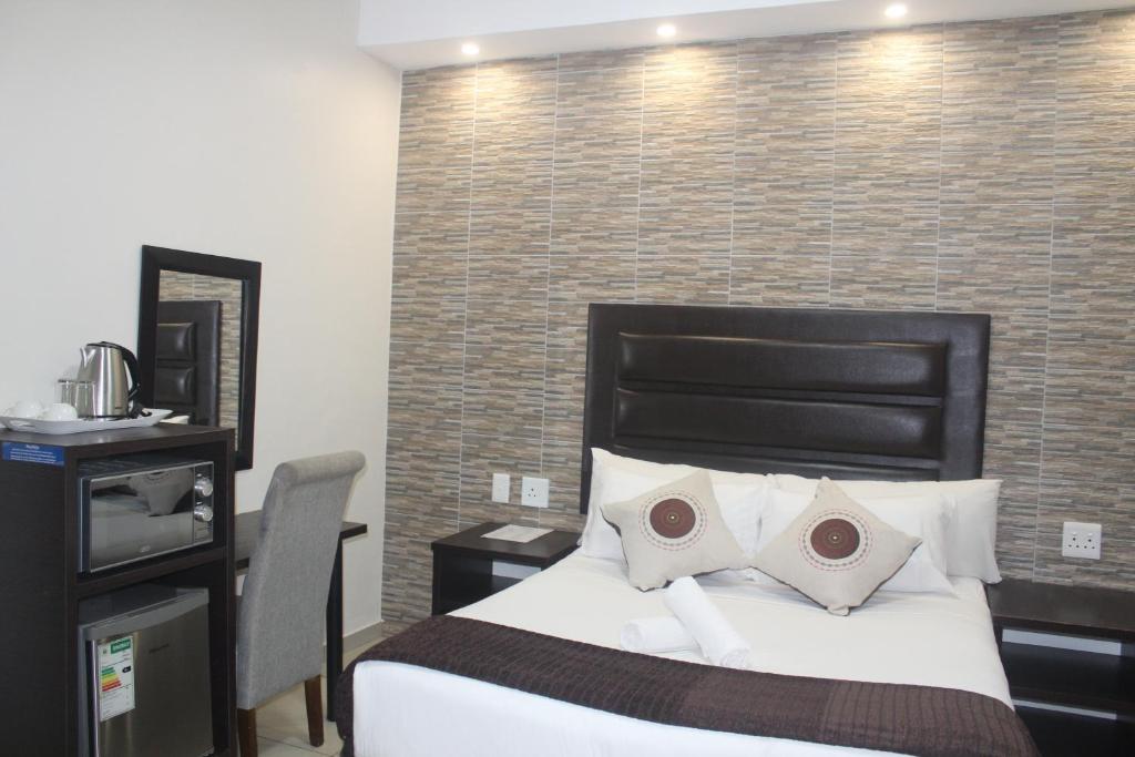 a bedroom with a bed and a brick wall at Bayside Lodge Empangeni in Empangeni