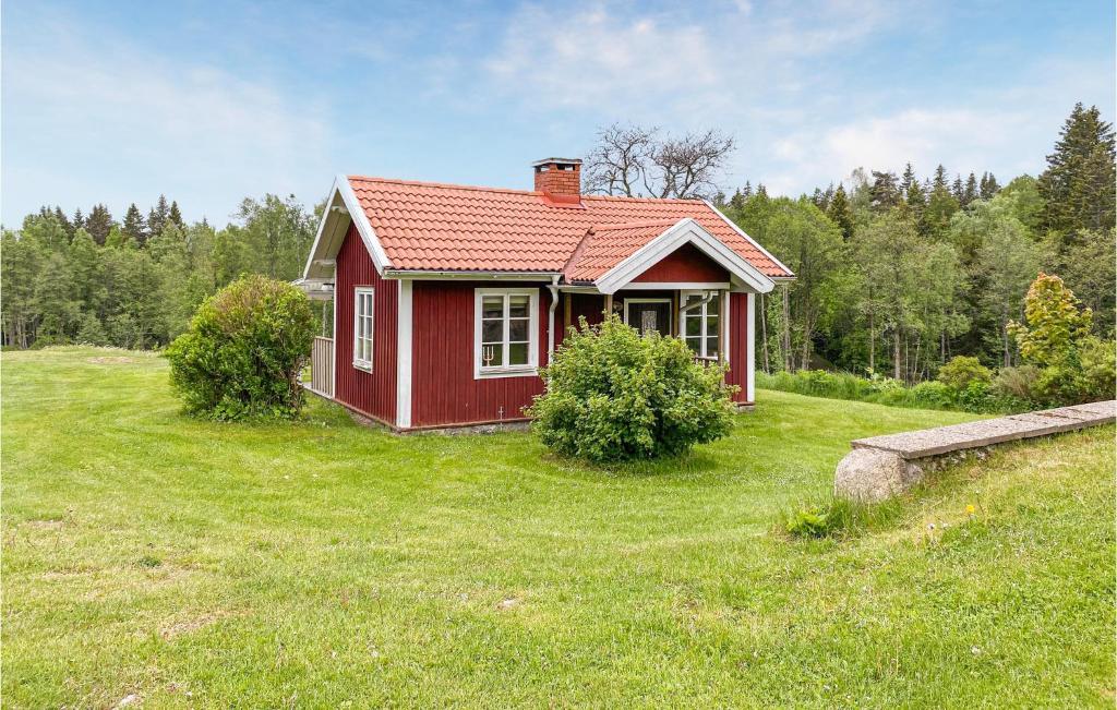 a small red house on a green field at Stunning Home In Tranhult With Kitchen 