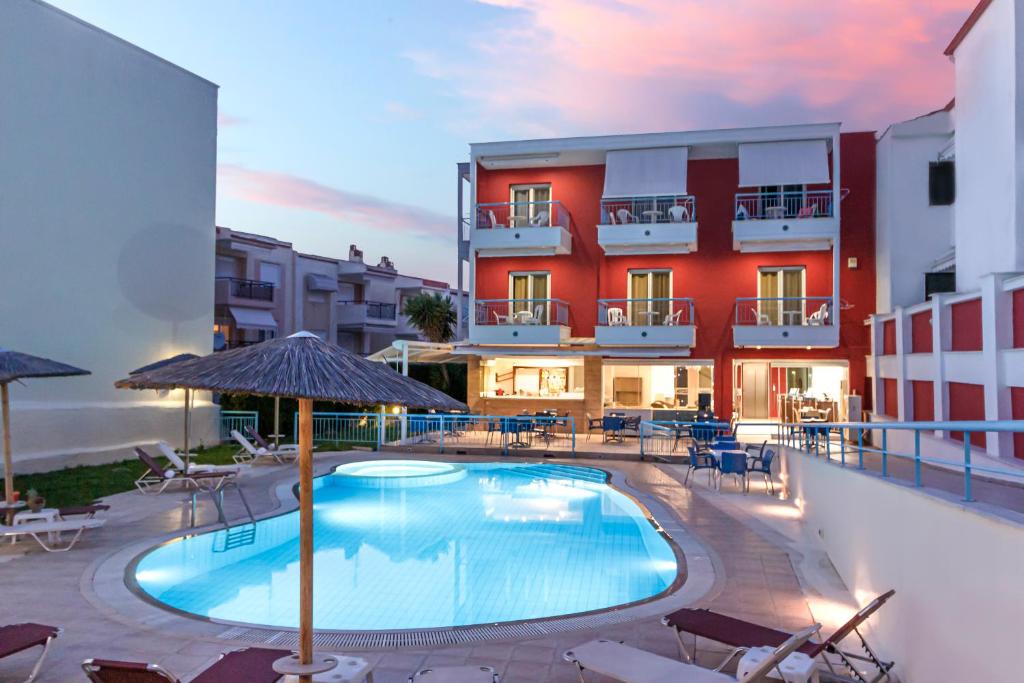 a hotel with a swimming pool in front of a building at Summer Dream Hotel in Polykhrono