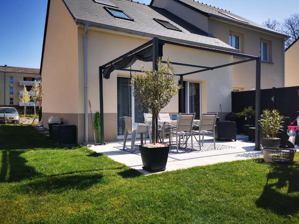 a patio with a table and chairs in a yard at Chambre chez particulier proche circuit 24h in Le Mans