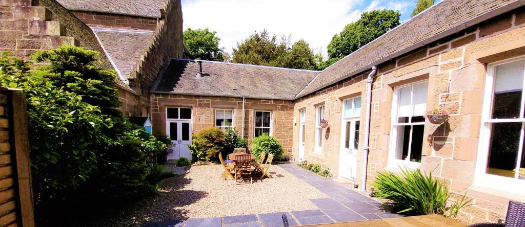 um pátio vazio de um edifício antigo com mesas e cadeiras em Westwood Cottage em Dundee