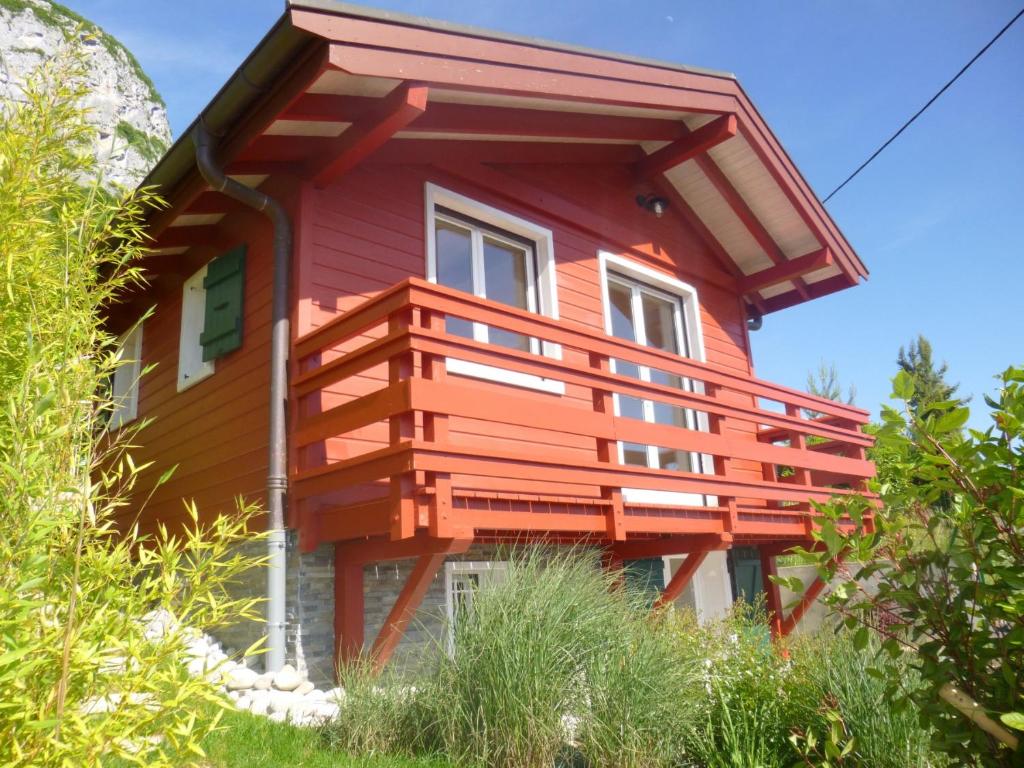 una casa roja con un balcón en el lateral. en Le cottage de Veyrier, très jolie vue Lac - LLA Selections by Location Lac Annecy en Veyrier-du-Lac