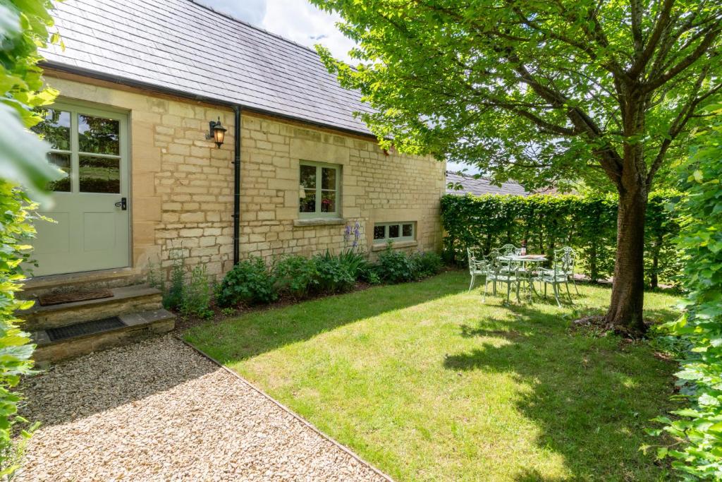 a backyard with a white door and a table and chairs at Stable Cottage, Freams Farm in Painswick