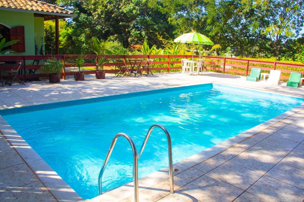 una piscina con sillas y sombrilla en Pousada Alecrim, en Serra do Cipo