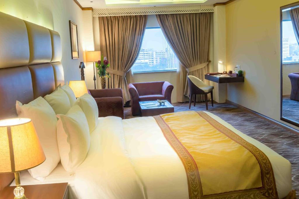 a hotel room with a large bed and a desk at Luxus Grand Hotel in Lahore
