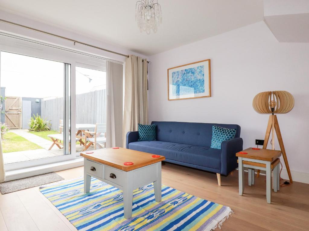 ein Wohnzimmer mit einem blauen Sofa und einem Tisch in der Unterkunft 6 Ocean Heights in Newquay