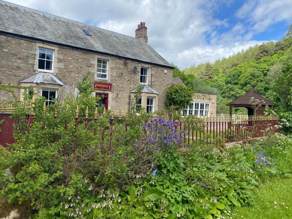 an old stone house with a garden in front of it at The Elks Head Inn in Whitfield