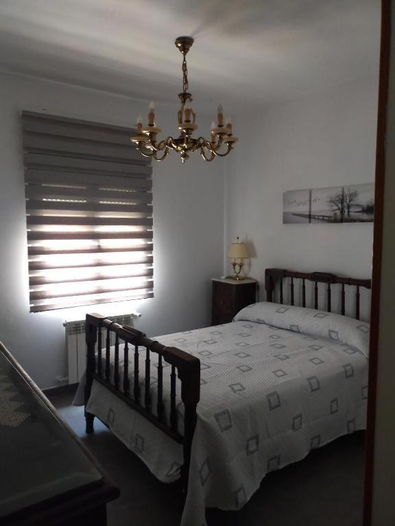 a bedroom with a bed and a chandelier and a window at Casa Carmen in Bargas