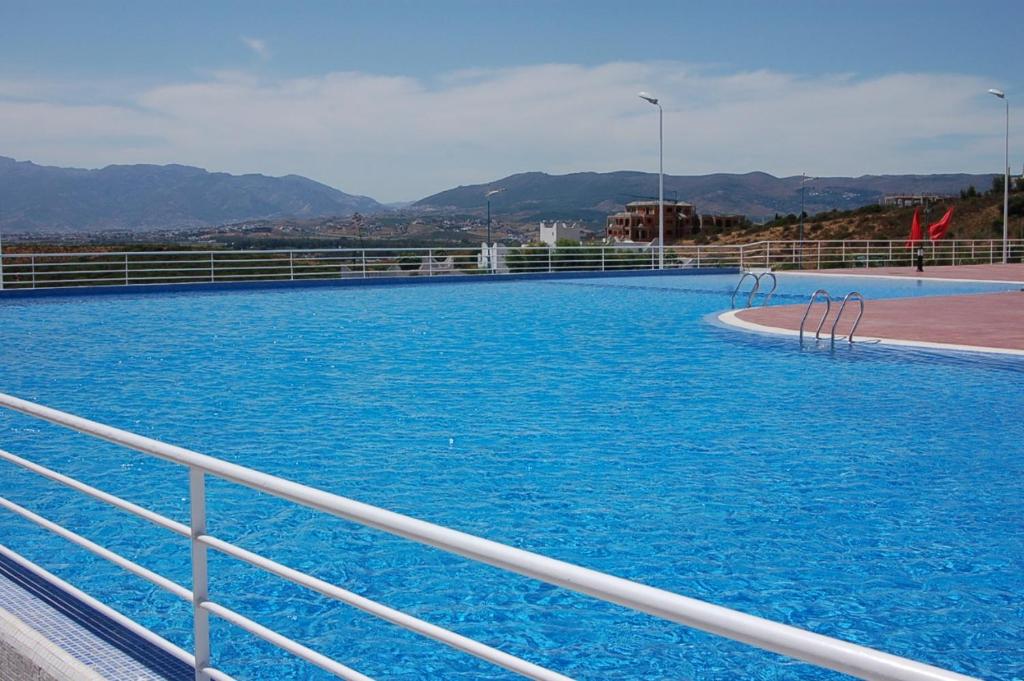 ein großer Pool mit blauem Wasser neben einem Zaun in der Unterkunft Cabo dream in Tétouan