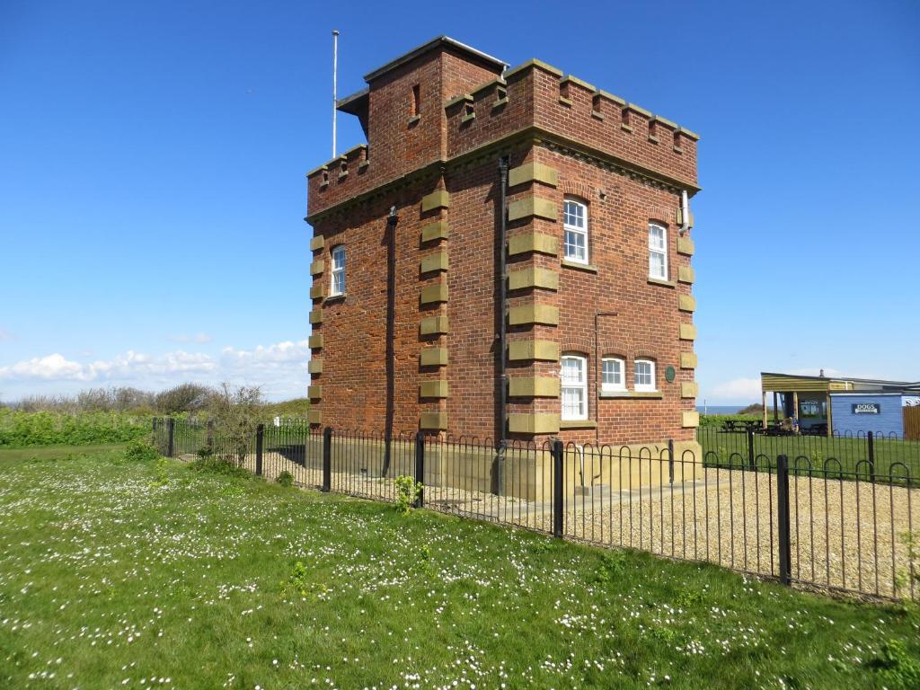 an old brick building with a fence around it at Coastguard Lookout in Hunstanton