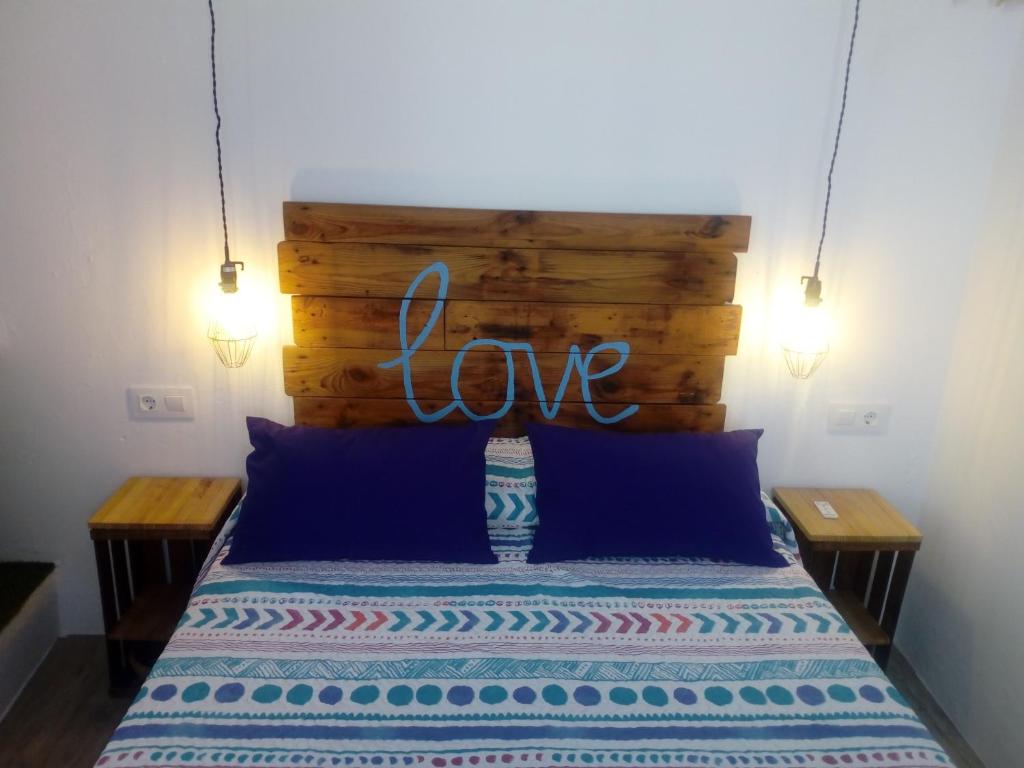 a bed with a sign that says love above it at El Escondite de Vejer in Vejer de la Frontera