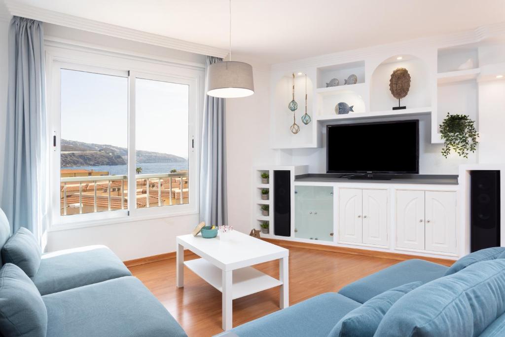 un salon avec un canapé bleu et une télévision dans l'établissement Home2Book Sunny & Quiet Beach House, Pool, à Candelaria