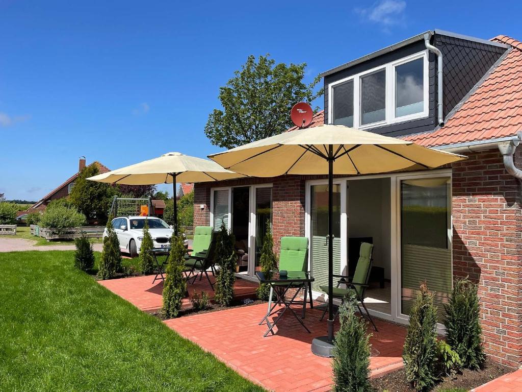 ein Haus mit zwei Sonnenschirmen und Stühlen auf einer Terrasse in der Unterkunft Marions Apartments Greetsiel in Greetsiel