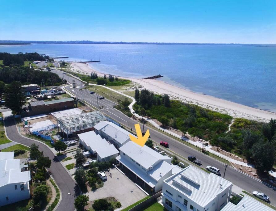 Silver Beach Penthouse في Kurnell: اطلالة جوية على شاطئ ومبنى ذو منحوتة صفراء كبيرة