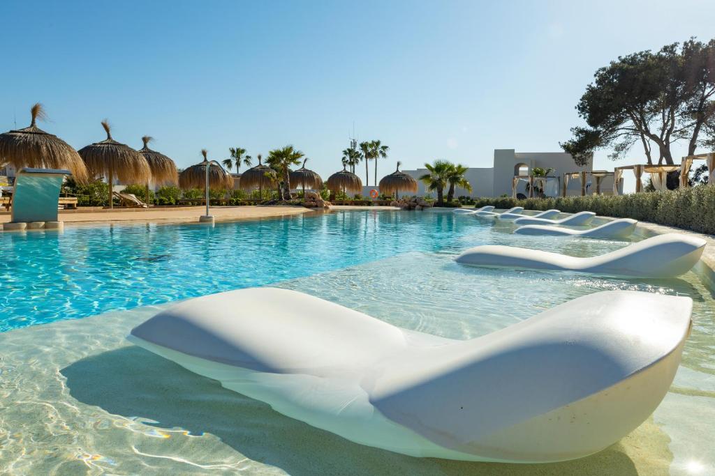 a swimming pool with white chairs in the water at Eques Petit Resort in Cala d´Or
