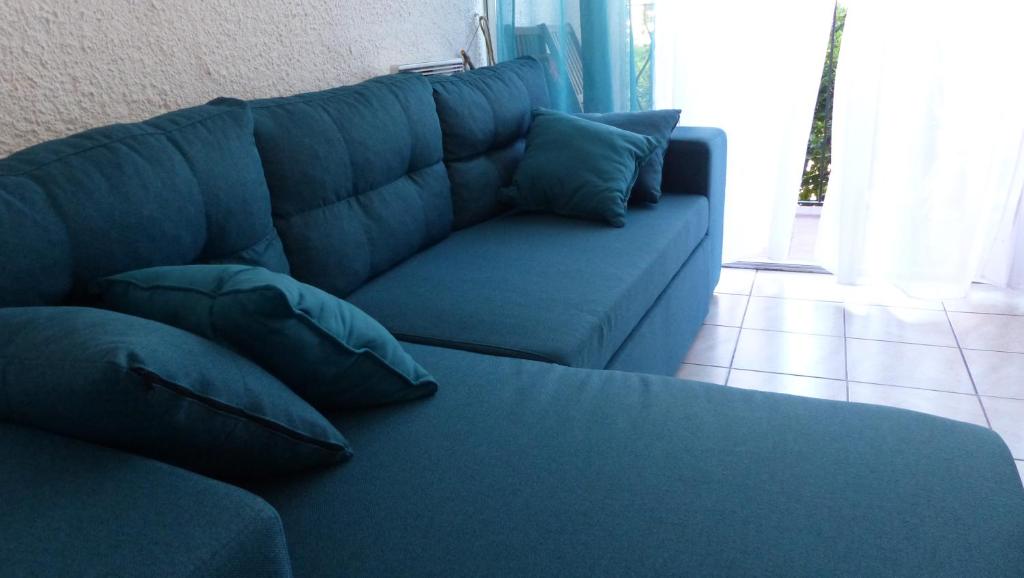un canapé bleu avec des coussins dans un salon dans l'établissement BELLE VUE sur MER au CALME, à Argelès-sur-Mer