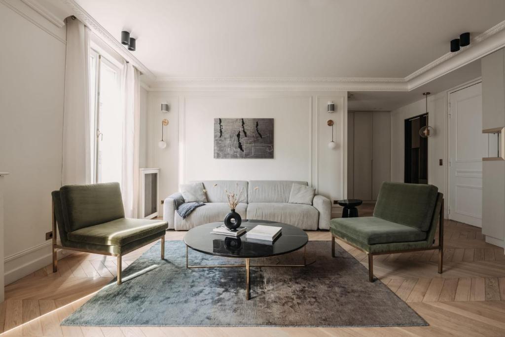 uma sala de estar com um sofá e duas cadeiras e uma mesa em HIGHSTAY - Luxury Serviced Apartments - Louvre-Rivoli em Paris