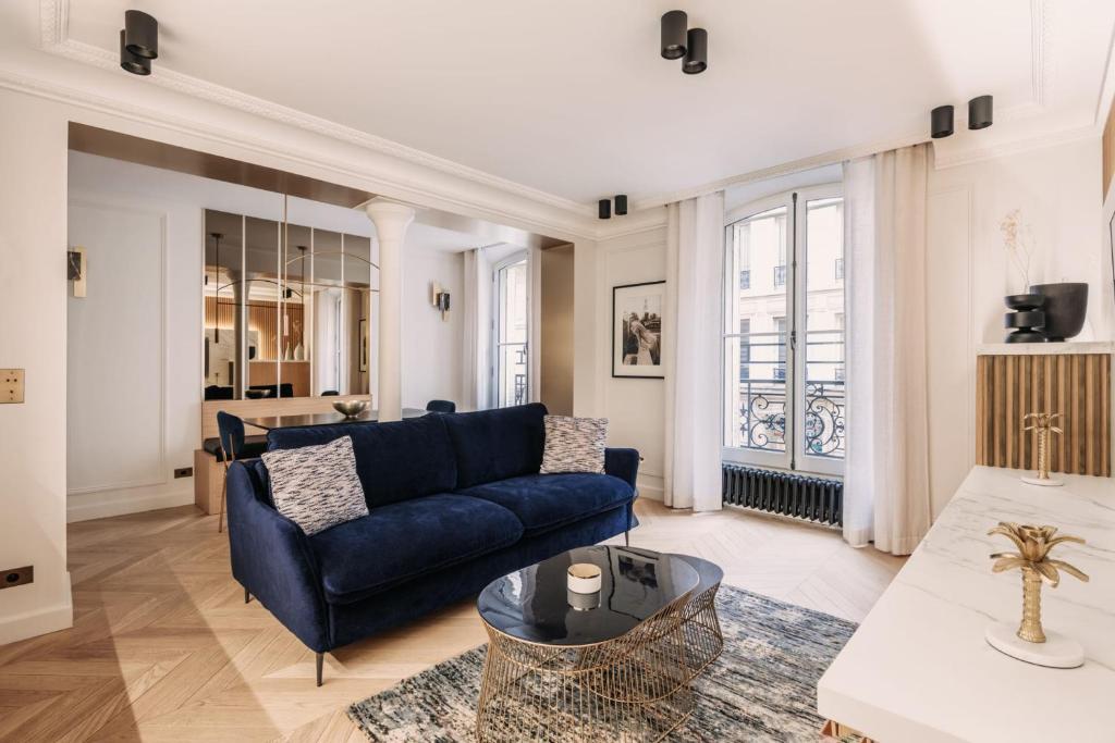 a living room with a blue couch and a table at HIGHSTAY - Luxury Serviced Apartments - Louvre-Rivoli in Paris