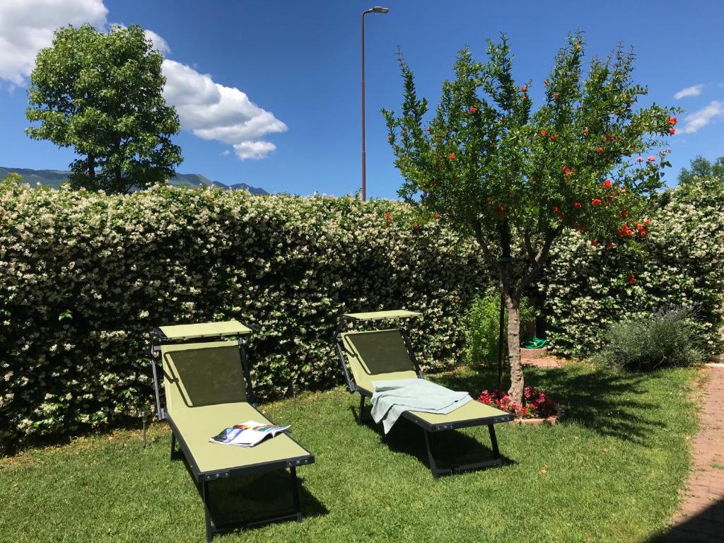 trzy krzesła ogrodowe siedzące w trawie obok drzewa w obiekcie Casa con vista Forte - tra lago e monti w mieście Rivoli Veronese