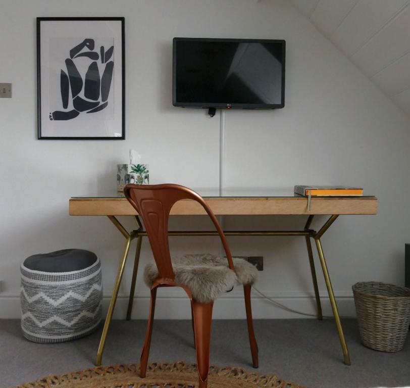 a desk with a chair and a television on a wall at DINCKLEY COURT BOUTIQUE RIVERSIDE ROOMS - Burcot on Thames in Abingdon