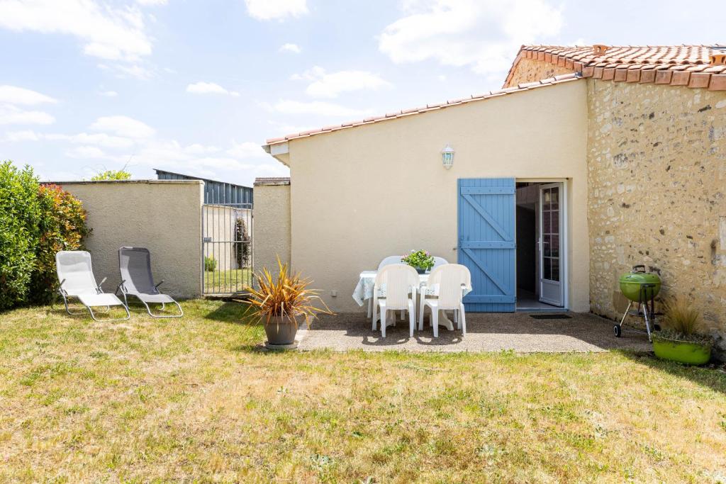 un patio con sedie bianche e un tavolo di fronte a una casa di La Saumuroise ad Antoigné