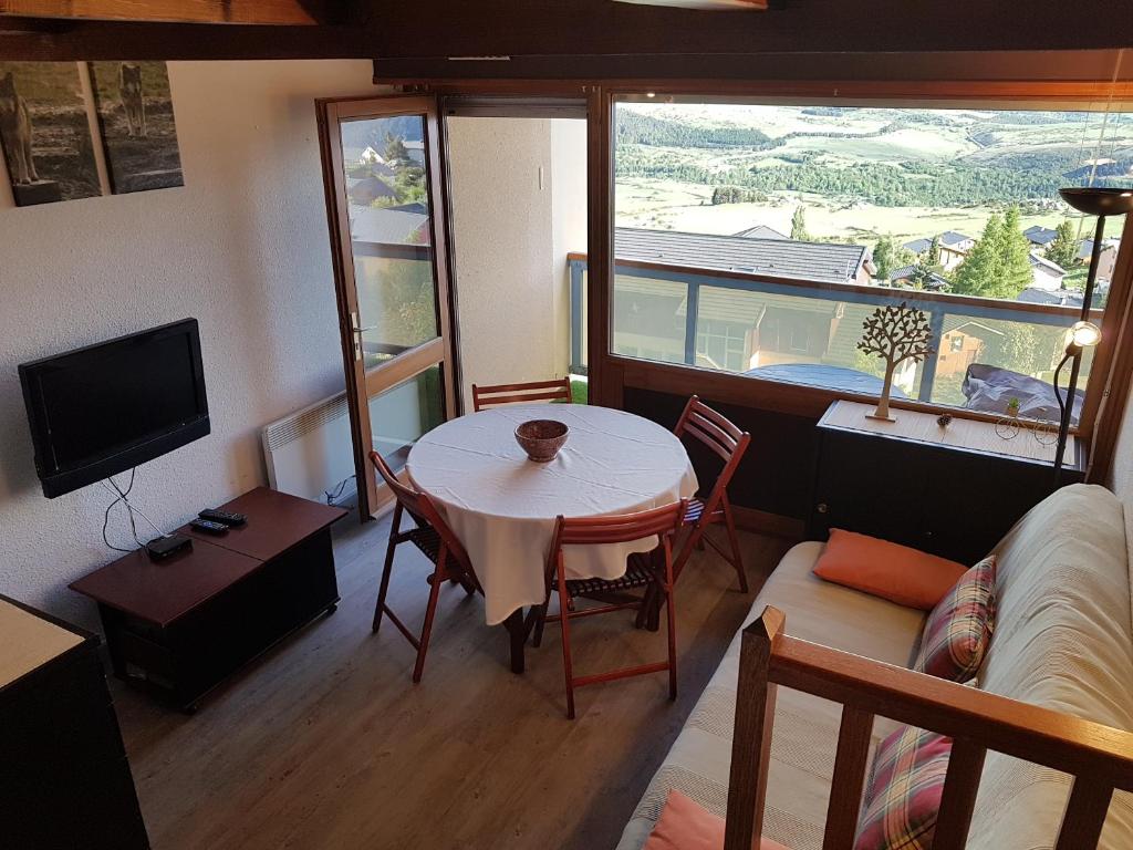 Elle comprend un petit salon avec une table et une télévision. dans l'établissement Font-Romeu Appart T2 + Cabine - Vue panoramique, à Font-Romeu-Odeillo-Via
