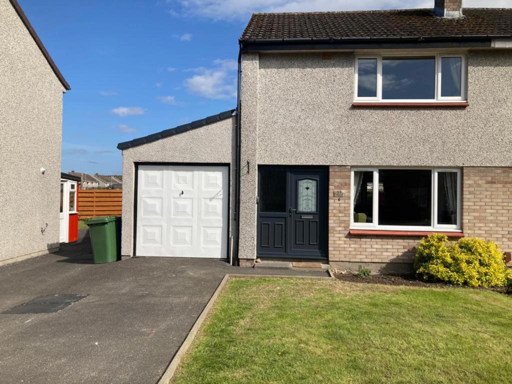 a house with white garage doors and a driveway at 3bedroom 1bathroom 1 shower room in quiet area in Inverness