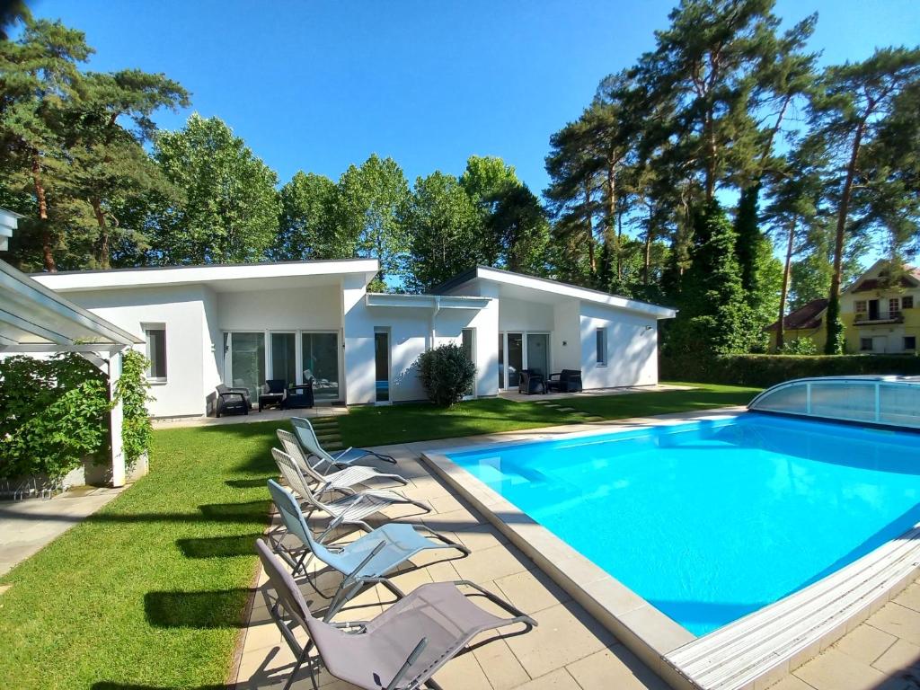 a house with a swimming pool and lounge chairs at Villa Bori Siófok in Siófok